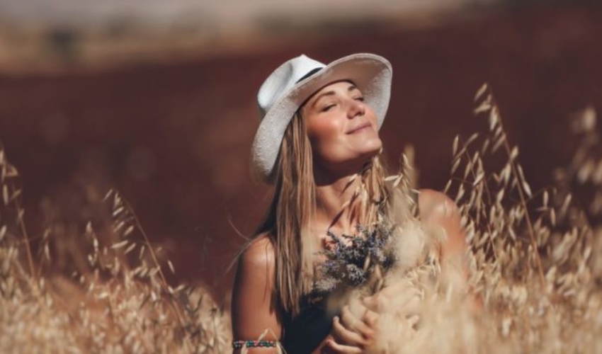 une femme avec un chapeau est assis dans un champ de ble