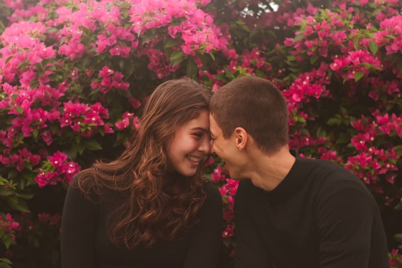 Un couple aimant souriant assis dehors dans les fleurs