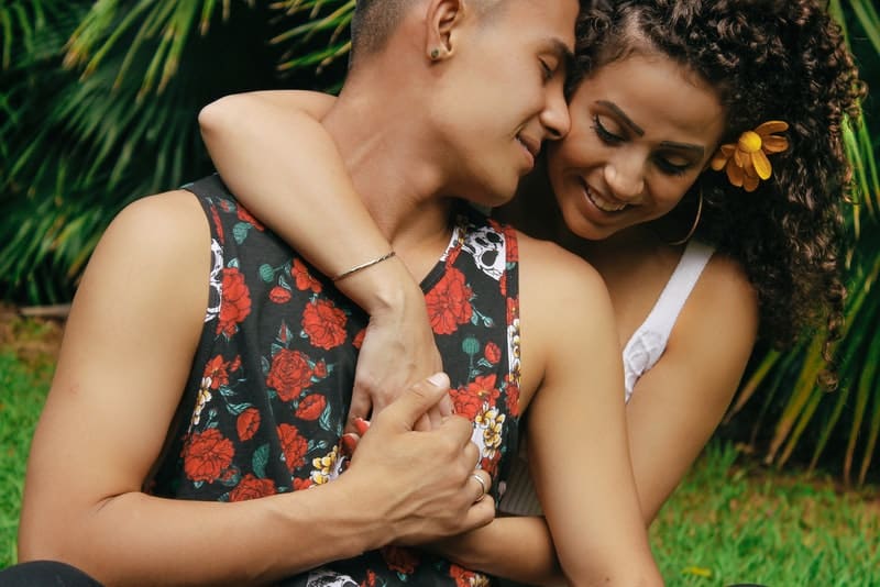 Un couple d'amoureux heureux assis sur l'herbe dans une étreinte