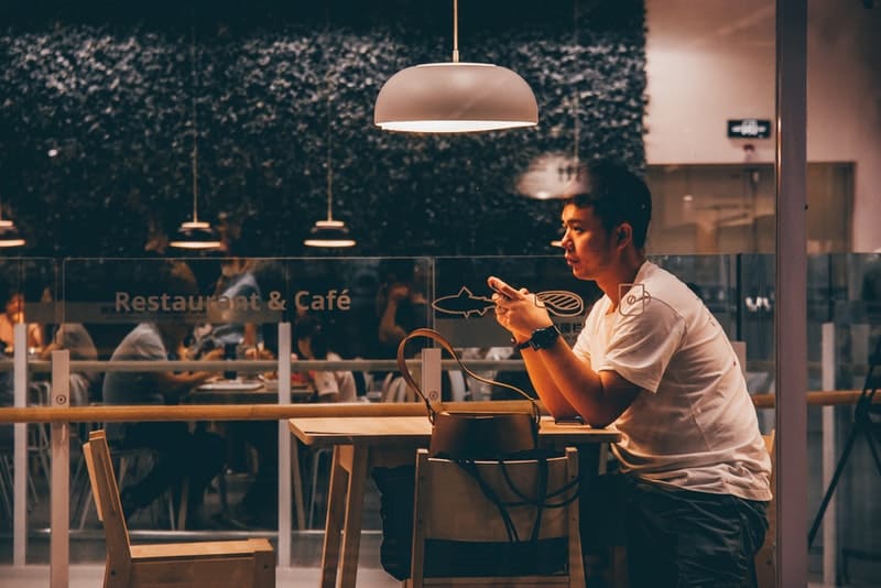 Un homme triste dans un T-shirt blanc assis seul dans un café