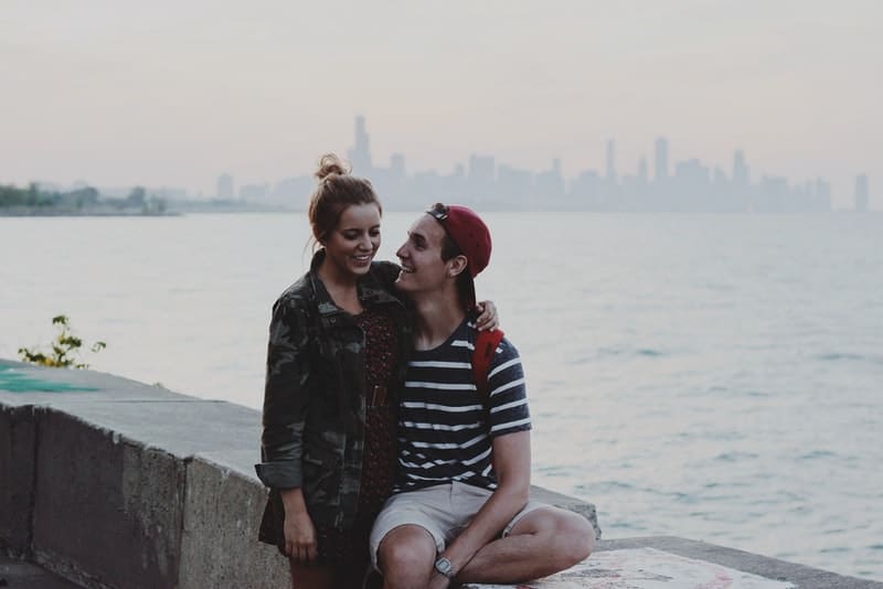 Un jeune couple amoureux assis sur du béton dans une étreinte