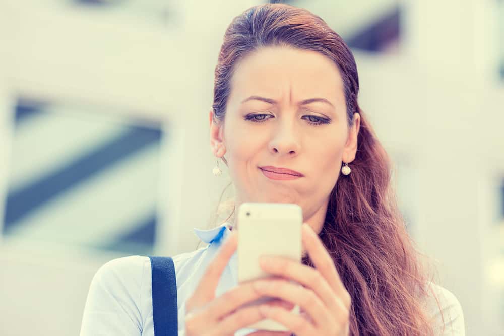 Un portrait d'une femme regardant malheureusement un smartphone
