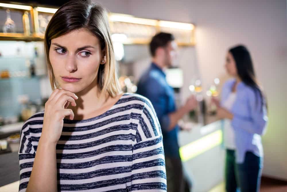 Un portrait d'une fille triste derrière laquelle se trouve un jeune couple aimant