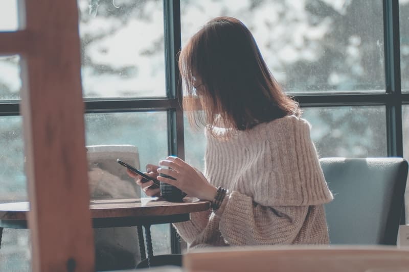Une femme assise à une table de boire du thé et d'écrire au téléphone