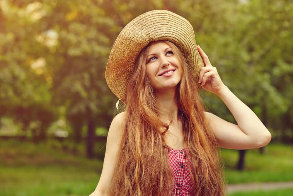 Une jolie femme heureuse avec un chapeau debout dans le parc