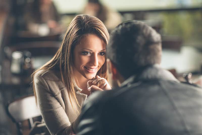 belle jeune femme écoutant l'homme dans le bar