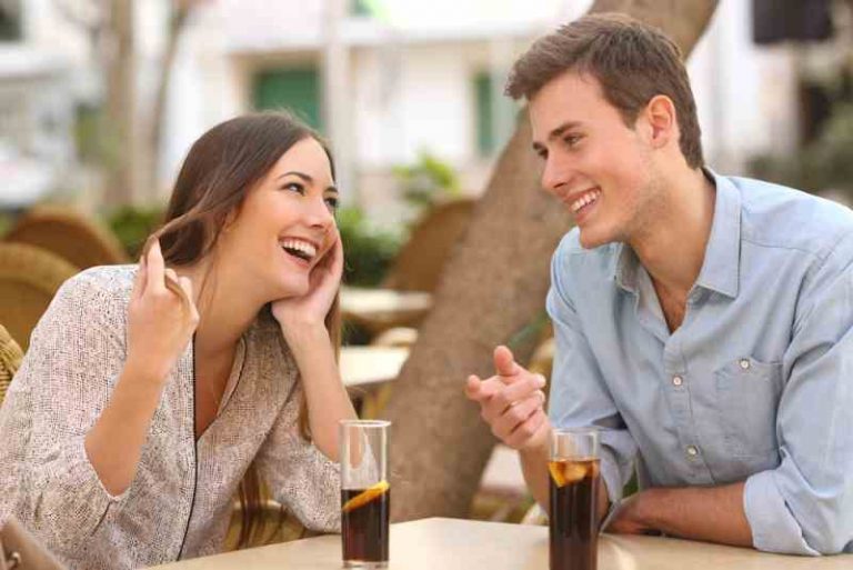 Une femme flirte avec un homme assis à une table à l'extérieur