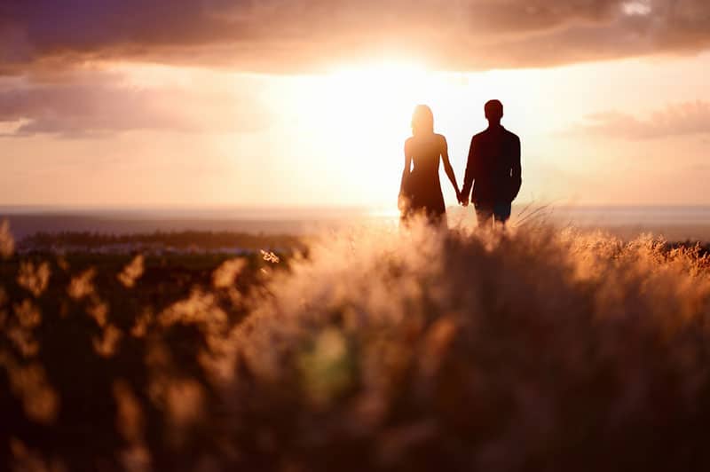 couple appréciant le coucher du soleil dans le pré