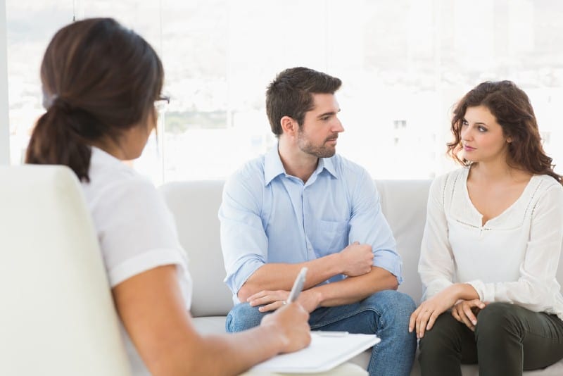 Couple assis sur un canapé à parler avec leur thérapeute au bureau