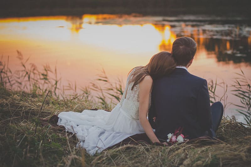 couple de mariage assis au bord du lac