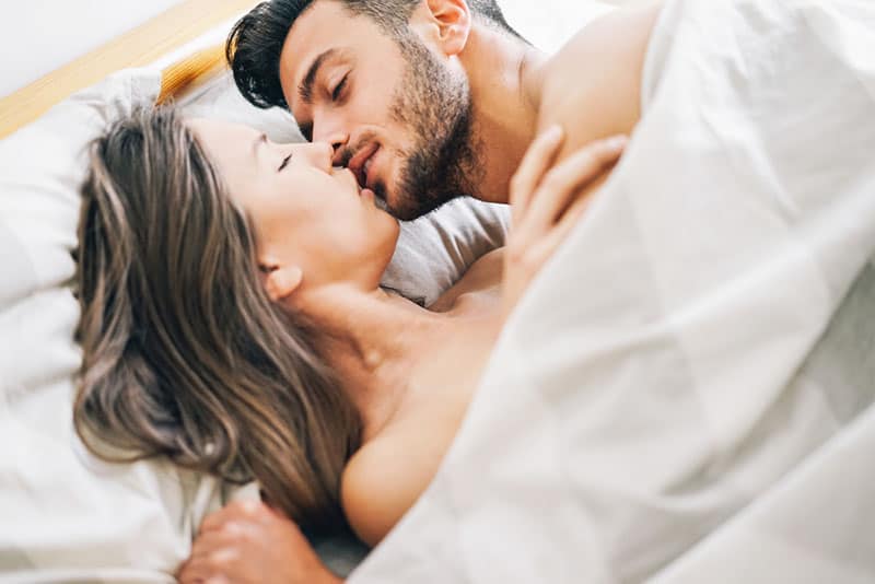 couple passionné s'embrassant au lit