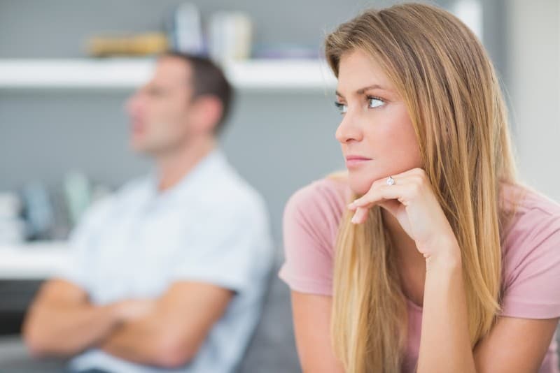 Couple triste assis sur le canapé dans le salon à la maison