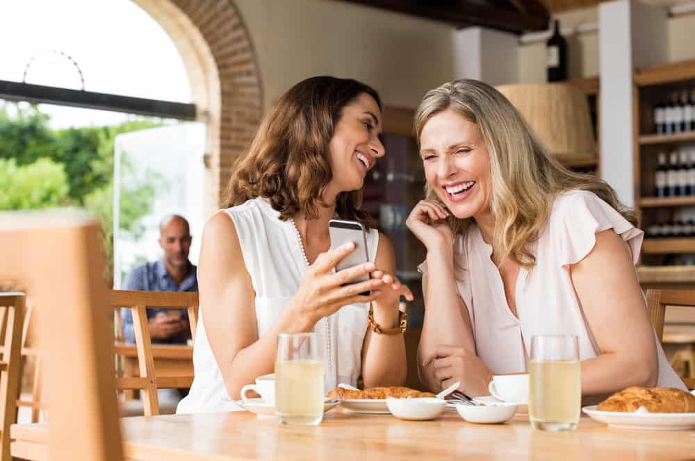 deux femmes prenant un café en riant