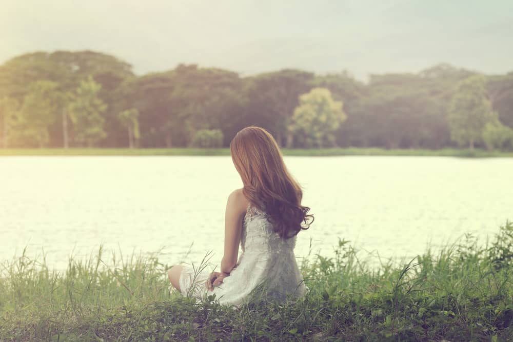 femme assise sur l'herbe au bord de la rivière