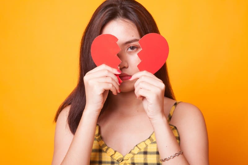 Belle jeune femme asiatique avec coeur brisé sur fond jaune