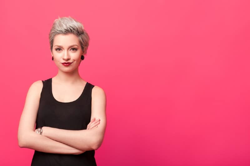 Femme confiante debout avec les bras croisés isolé sur fond rose