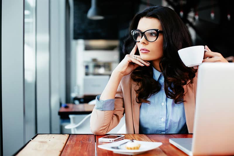 femme consciente regardant à distance et boire du café