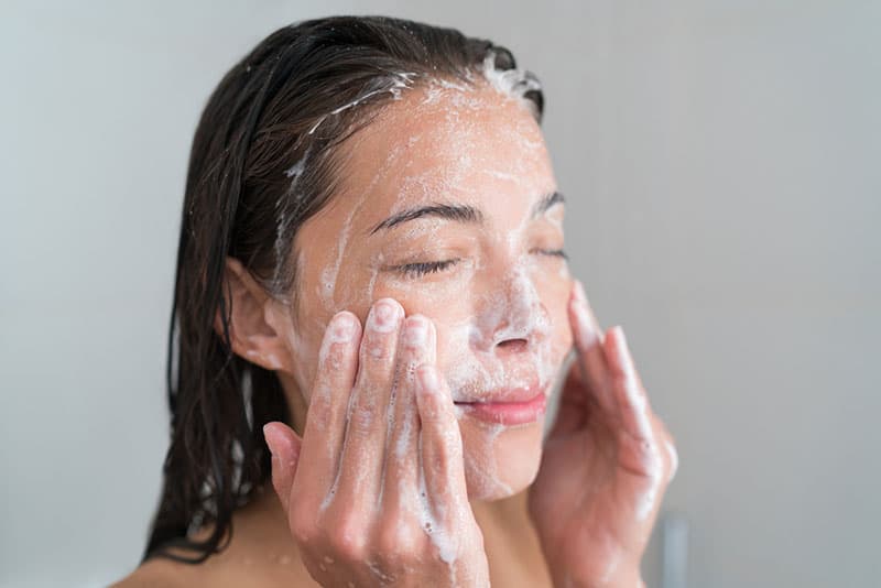 femme lavant son visage avec du savon