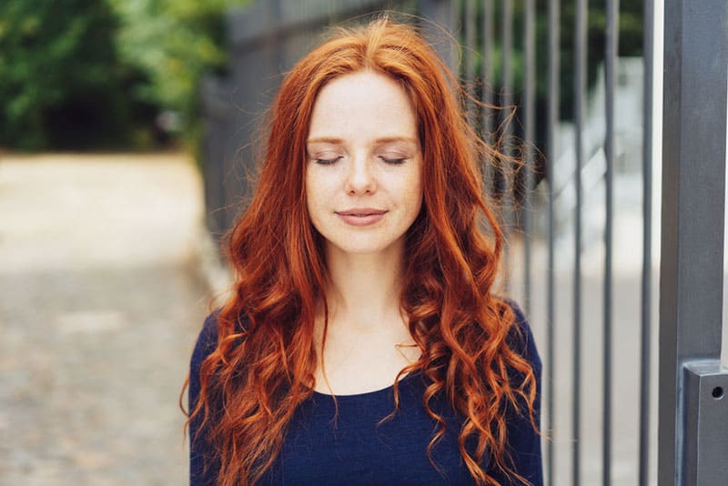 femme rousse debout en plein air avec les yeux fermés