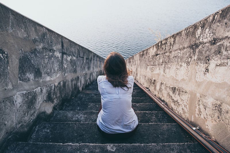 femme solitaire assise sur les escaliers et regarde la mer