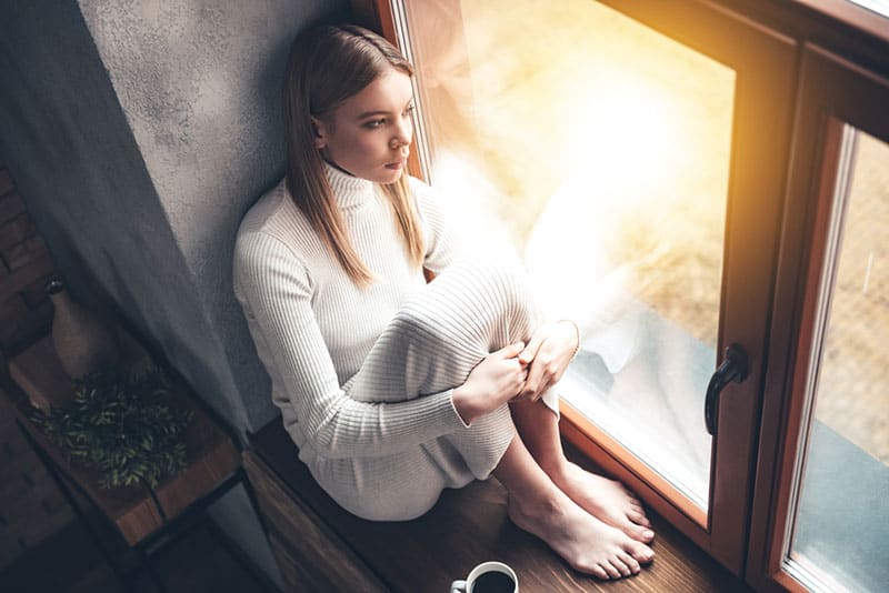 femme triste assise près de la fenêtre