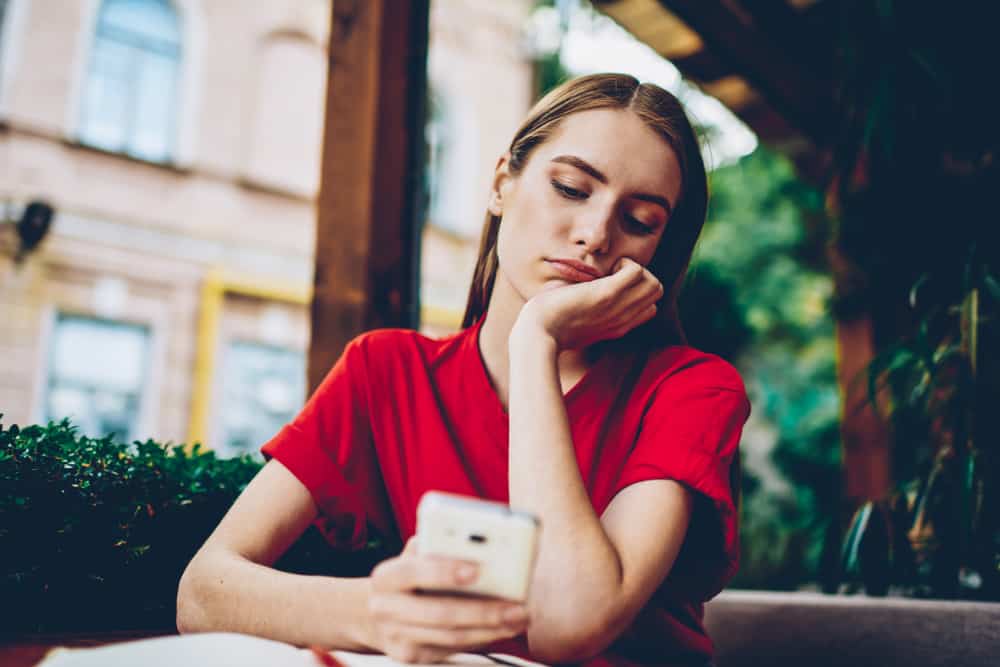 femme triste au bouton de la table sur le téléphone