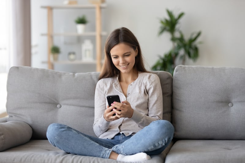 fille souriante assise sur le canapé et la clé sur le téléphone portable