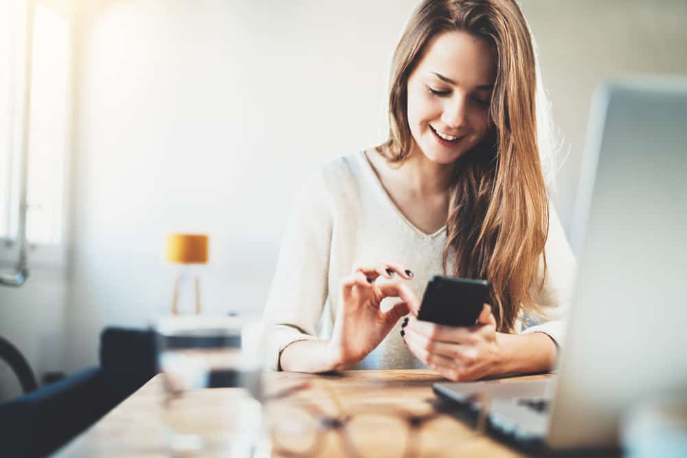 fille souriante heureuse écrit des sms