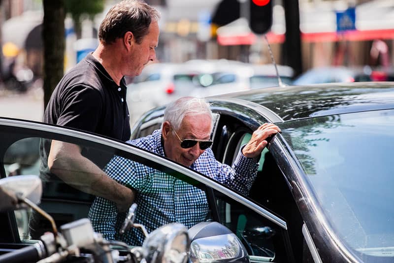 homme aidant un vieil homme à s'asseoir dans la voiture