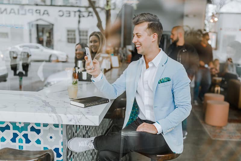 homme souriant en costume tapant au téléphone