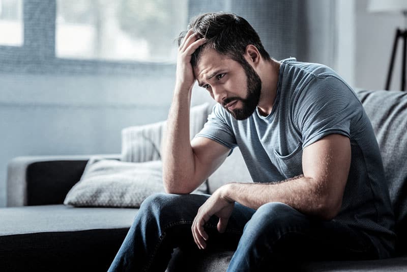 homme triste assis sur le canapé