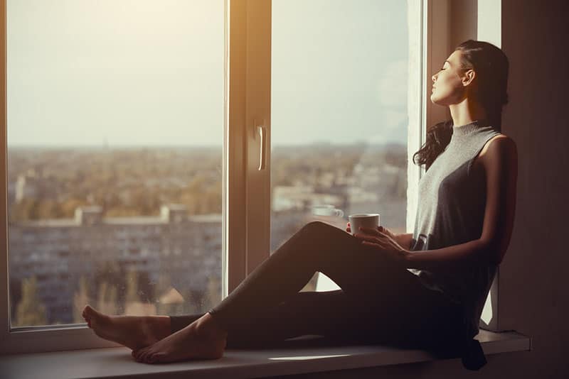 jeune femme buvant du café près de la fenêtre