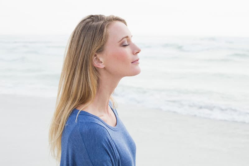 jeune femme prenant une profonde respiration sur la plage