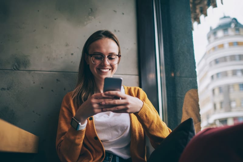 jeune fille avec bouton de lunettes sur téléphone portable