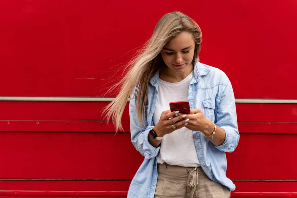 la blonde adossée au mur écrit des sms
