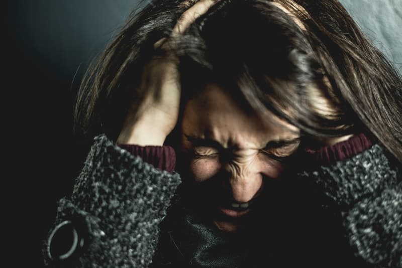 la brune hystérique hurle de façon déprimante et tient sa tête avec ses mains