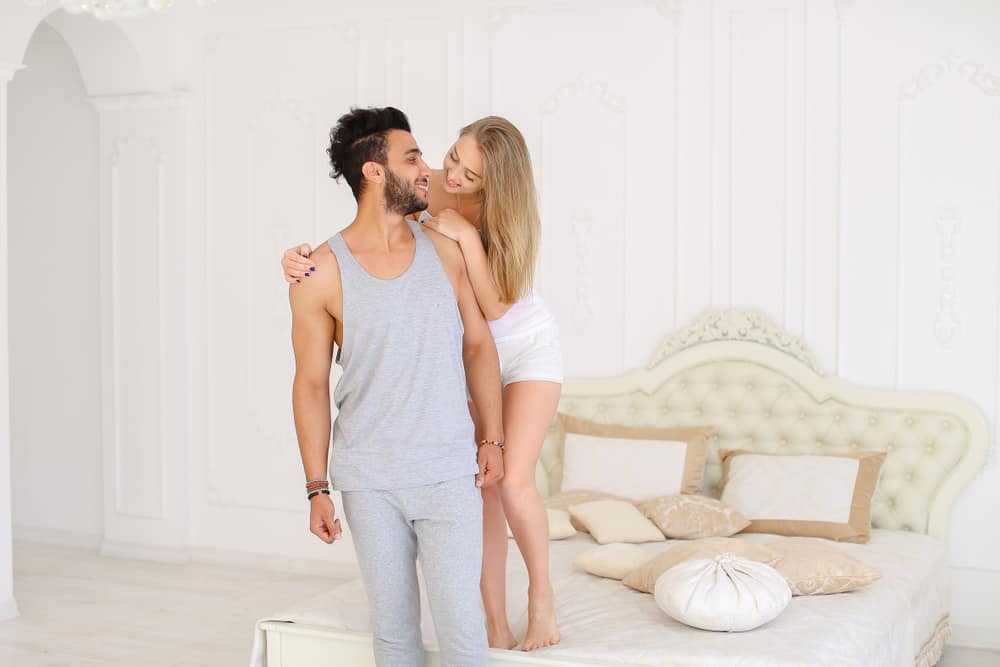 la femme embrasse l'homme à côté du lit et rit