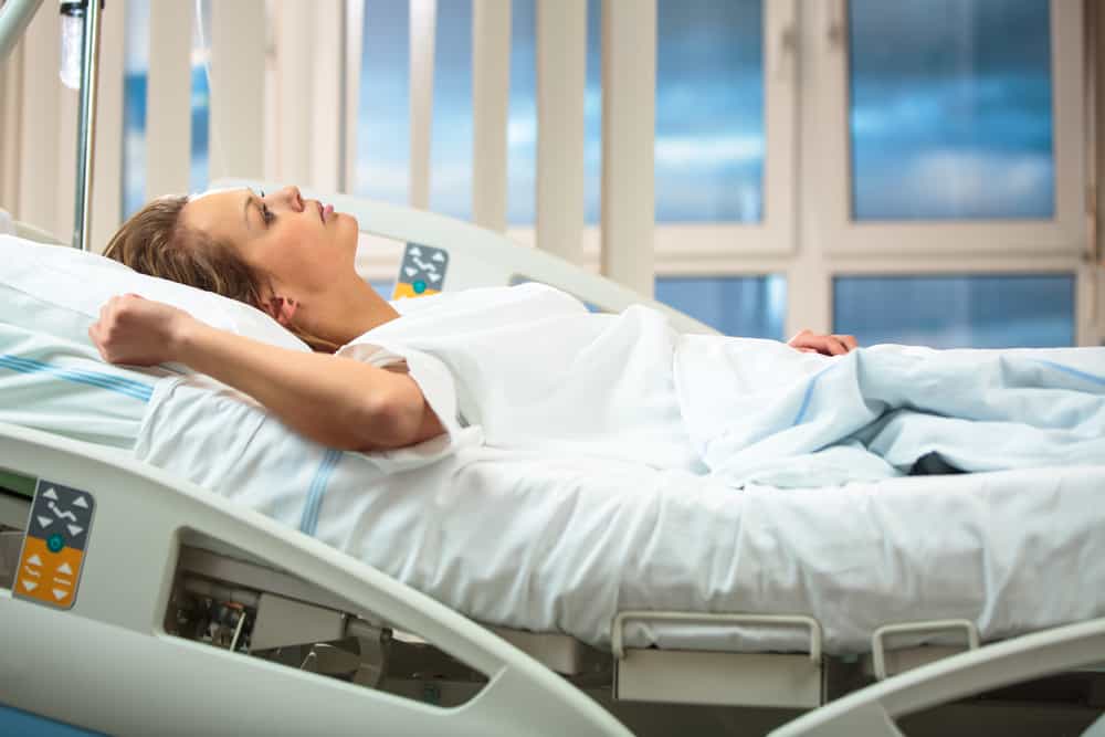 la femme est allongée dans un lit d'hôpital