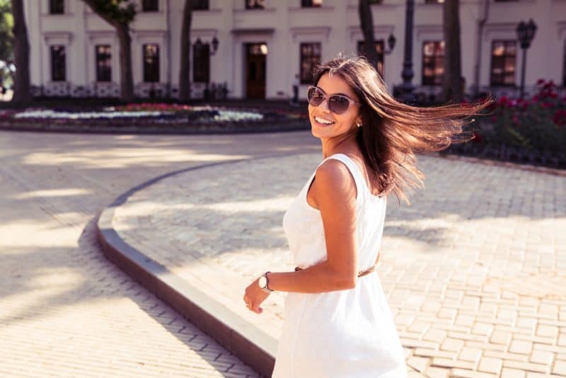 la femme marche dans la rue avec des lunettes sur la tête et rit
