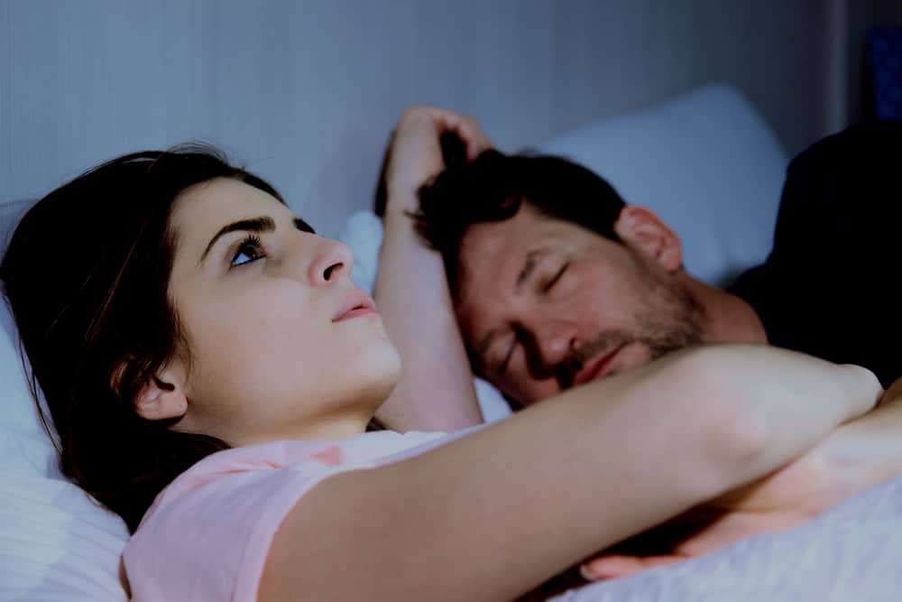la femme pense et se couche à côté de l'homme endormi
