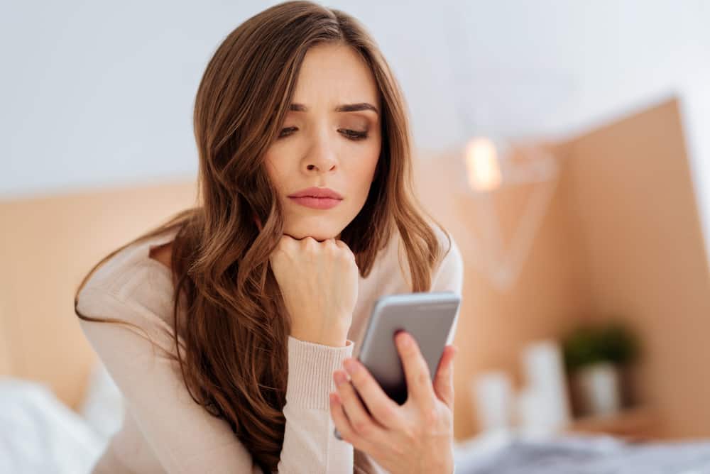 la femme pensive tient le téléphone dans sa main et le regarde