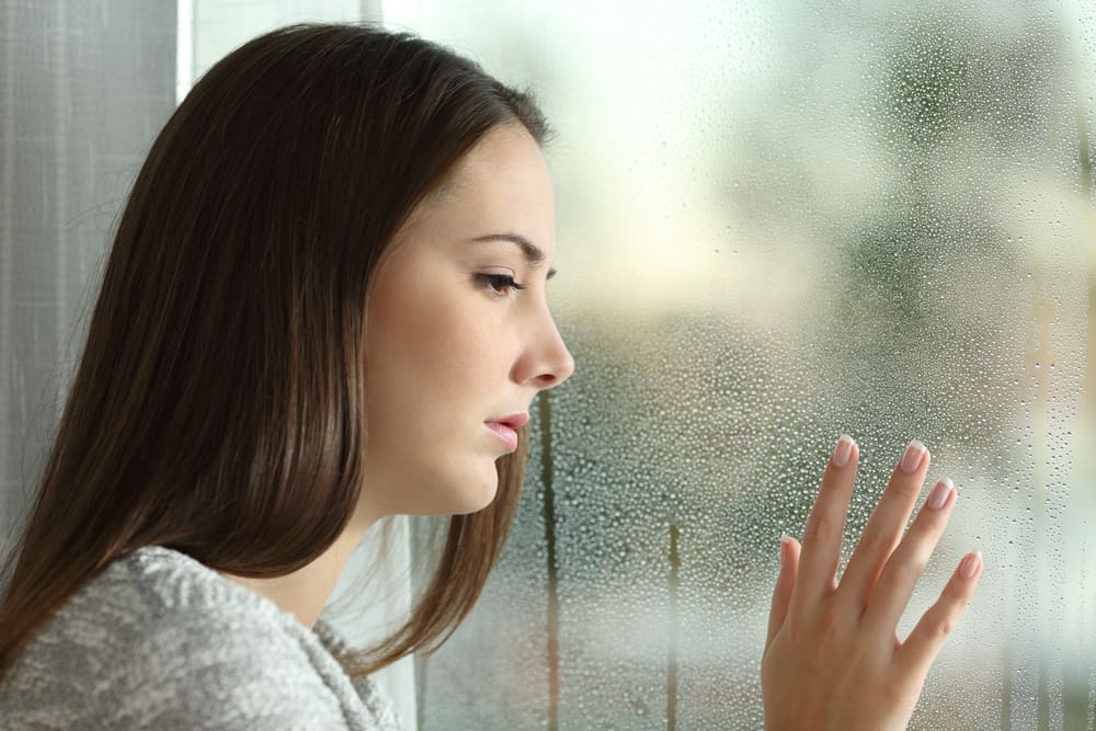 la femme regarde par la fenêtre déçue
