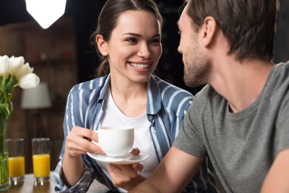 la femme rit avec du café à la main et regarde l'homme