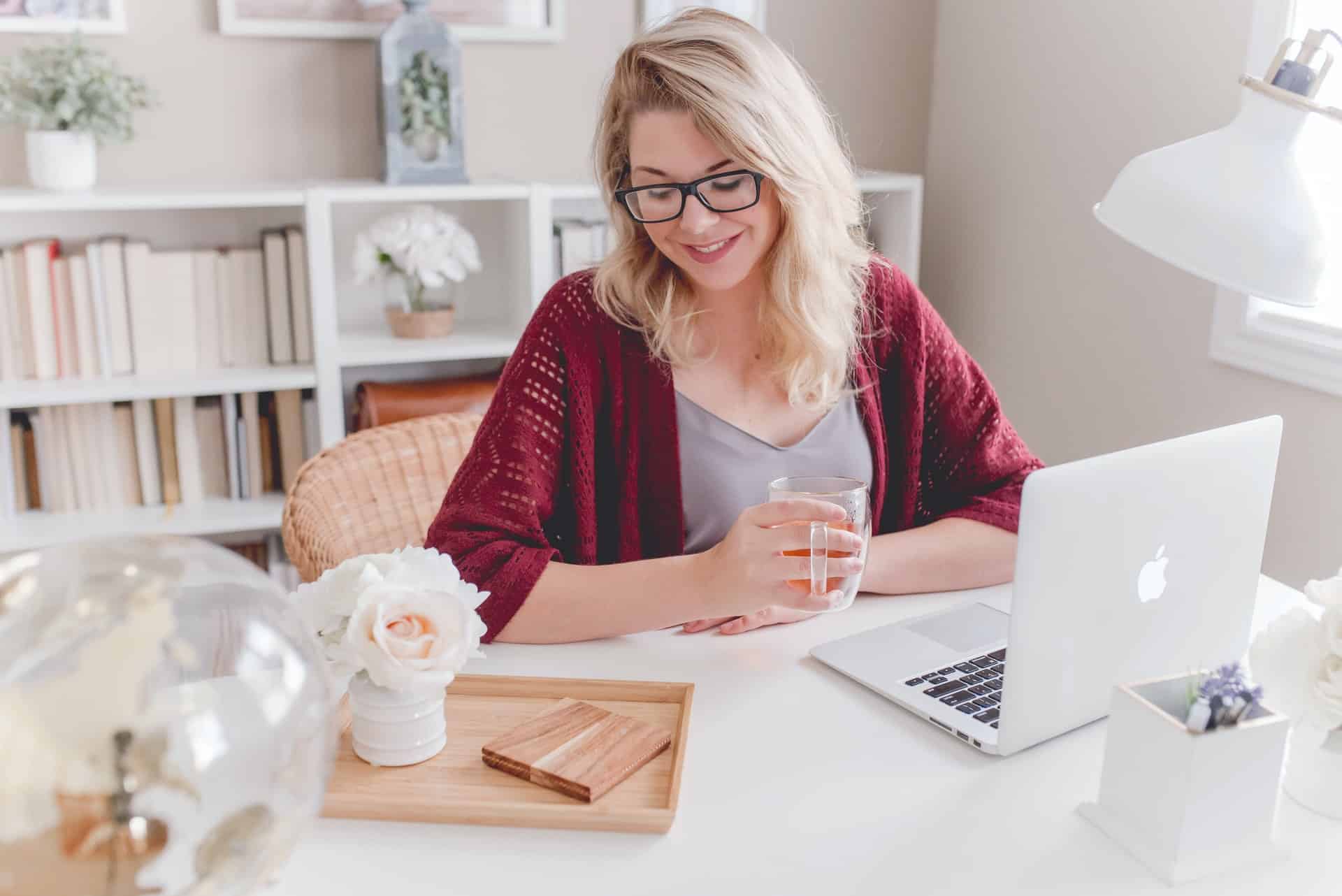 la femme s'assoit et travaille derrière l'ordinateur portable et sourit