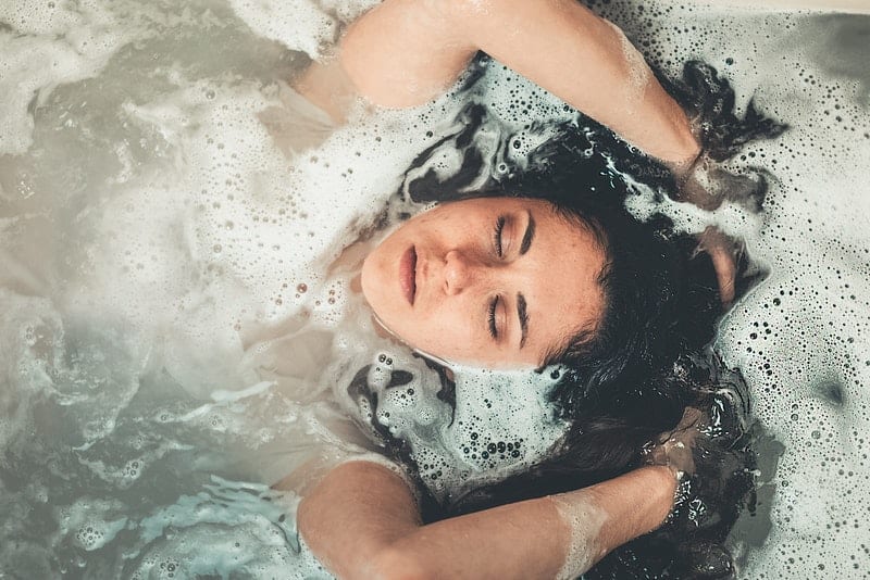 la femme se repose dans la baignoire les yeux fermés
