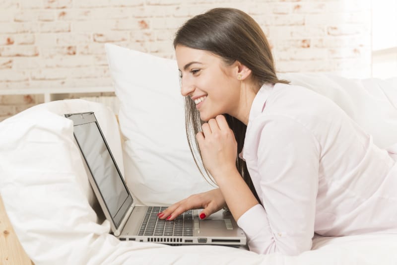 la fille est allongée sur le canapé et surfe sur Internet