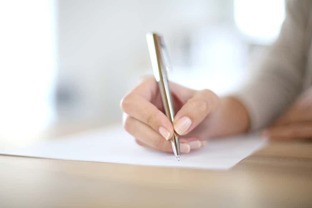 la main d'une femme écrit quelque chose sur du papier