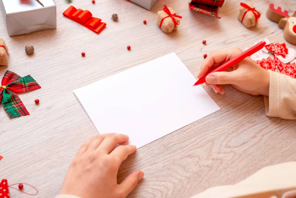 l'enfant à table écrit une carte de voeux