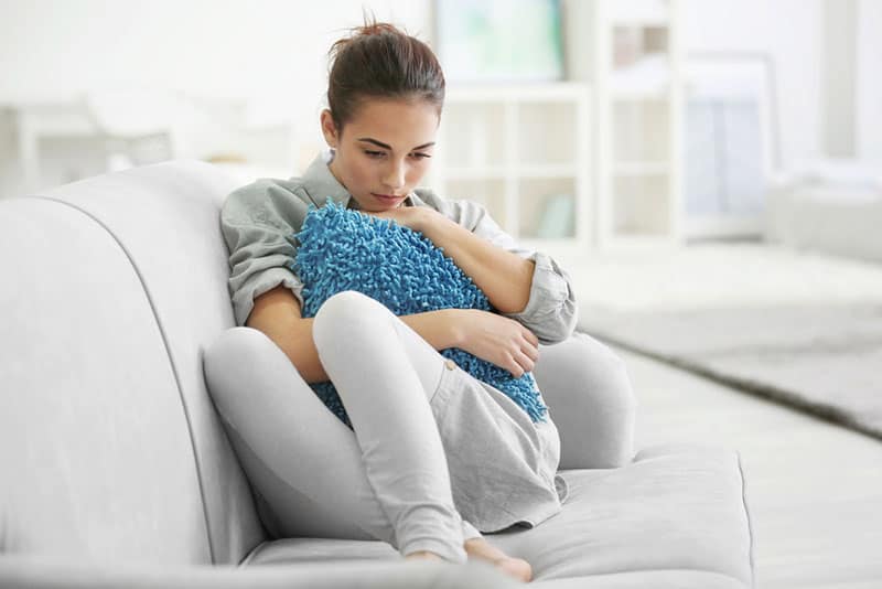triste jeune femme assise sur le canapé