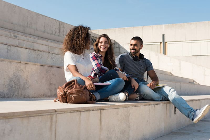 trois amis assis dehors dans les escaliers à parler